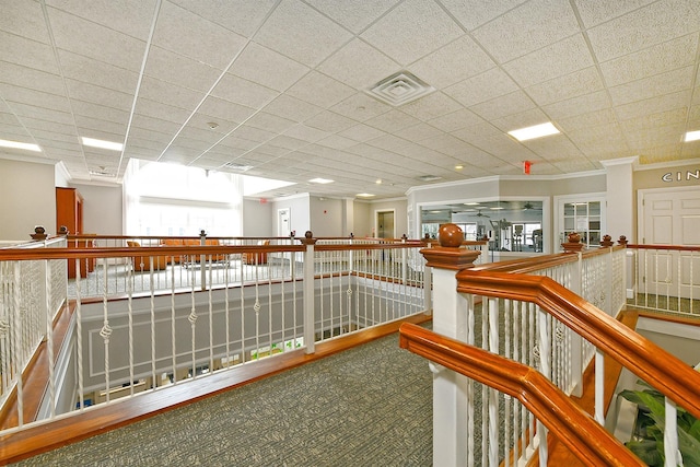 hallway with carpet, an upstairs landing, visible vents, and crown molding