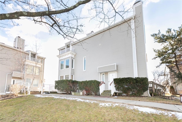 view of property exterior featuring entry steps, a yard, and a chimney