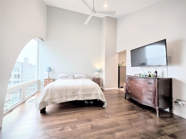 bedroom with visible vents, ceiling fan, wood finished floors, high vaulted ceiling, and baseboards