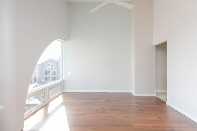 empty room featuring a high ceiling, wood finished floors, and baseboards