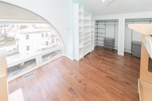 interior space with two closets, wood finished floors, visible vents, and baseboards