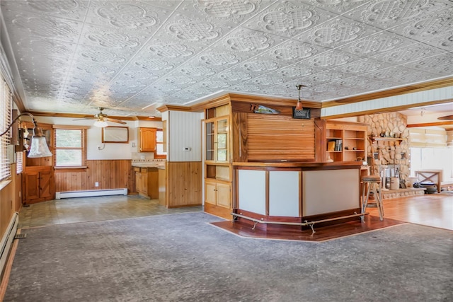 interior space with wainscoting, an ornate ceiling, crown molding, wood walls, and a baseboard heating unit