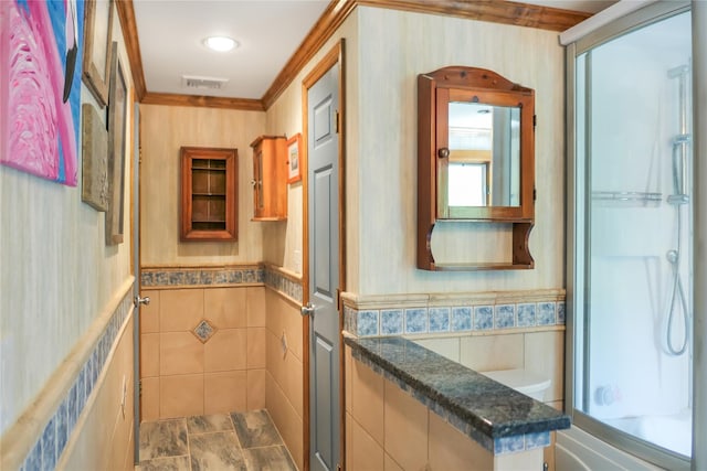 full bath with a wainscoted wall, a shower, visible vents, and tile walls