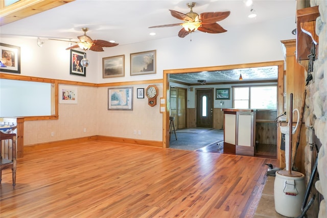 living area with a ceiling fan, baseboards, and wood finished floors