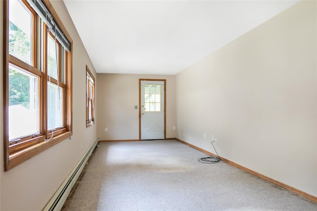 carpeted spare room featuring a baseboard heating unit and baseboards