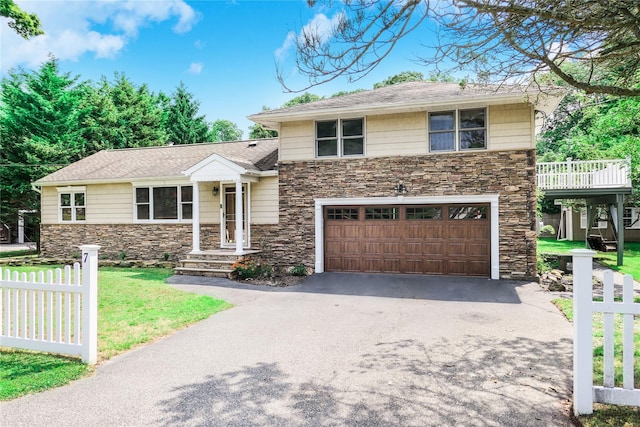 view of front of house featuring aphalt driveway, stone siding, fence, and a garage