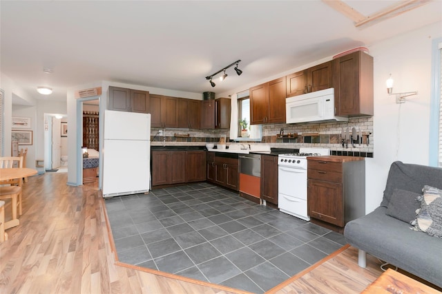 kitchen featuring decorative backsplash, white appliances, dark wood-type flooring, and a sink