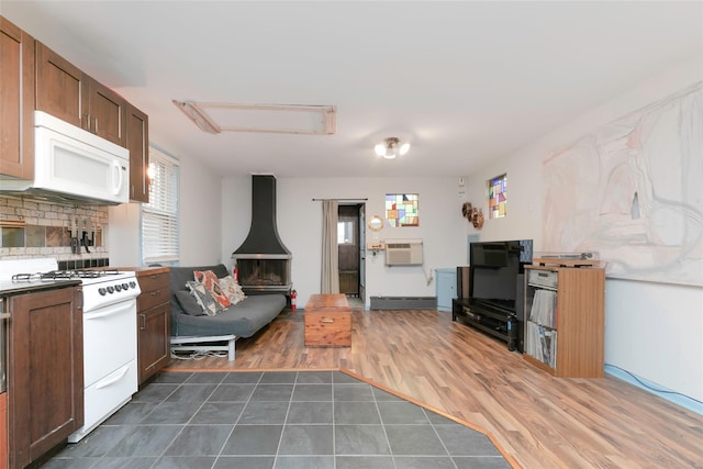kitchen featuring white appliances, an AC wall unit, a healthy amount of sunlight, and a baseboard radiator