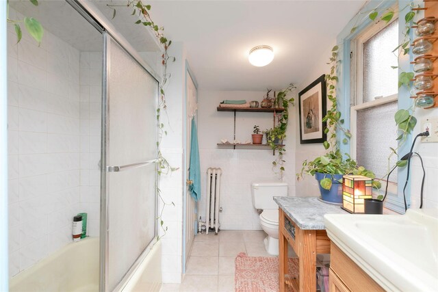 full bath featuring vanity, enclosed tub / shower combo, radiator heating unit, tile walls, and tile patterned floors