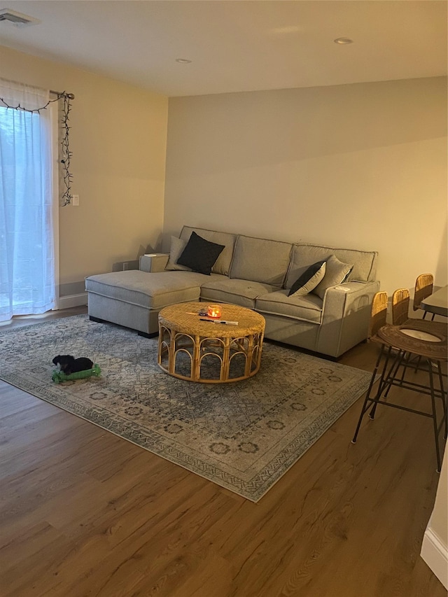 living room featuring wood finished floors, visible vents, and baseboards