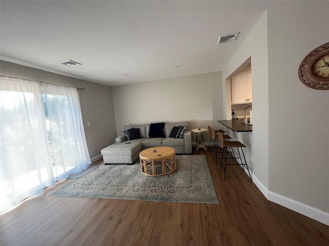 living room with dark wood-type flooring, visible vents, and baseboards