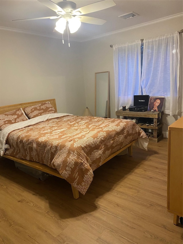 bedroom featuring ceiling fan, visible vents, wood finished floors, and ornamental molding