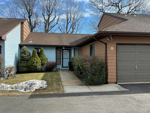 single story home featuring a garage and roof with shingles