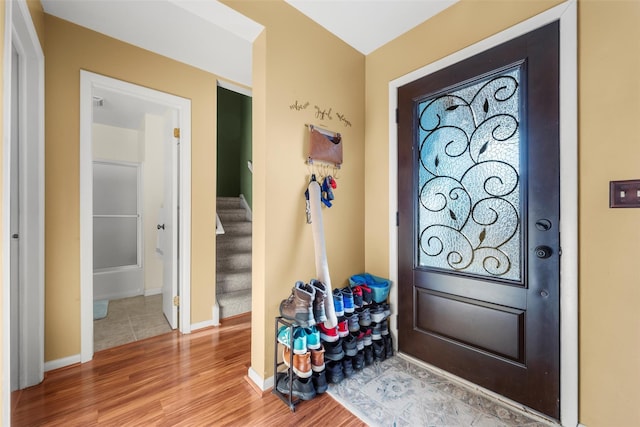 foyer with light wood-type flooring, stairway, and baseboards