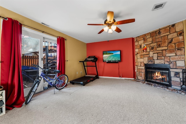 exercise area with ceiling fan, carpet, a fireplace, and visible vents