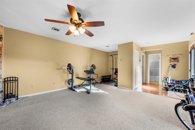 exercise area with baseboards, visible vents, ceiling fan, and light colored carpet