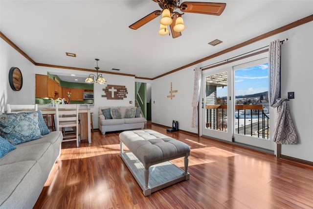 living area featuring ornamental molding, ceiling fan with notable chandelier, baseboards, and wood finished floors