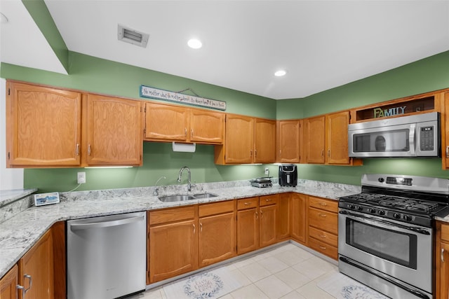 kitchen with stainless steel appliances, visible vents, a sink, and light stone counters