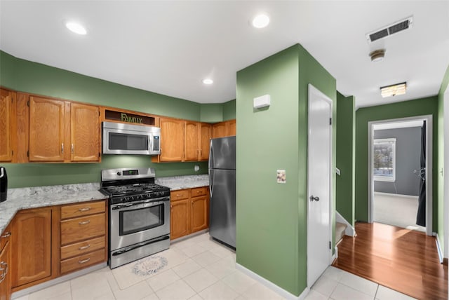 kitchen with visible vents, brown cabinetry, light stone countertops, stainless steel appliances, and recessed lighting