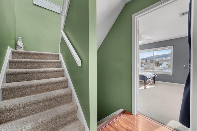 stairs with visible vents, baseboards, ceiling fan, and wood finished floors