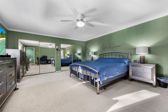 bedroom featuring multiple closets, light colored carpet, ceiling fan, and ornamental molding