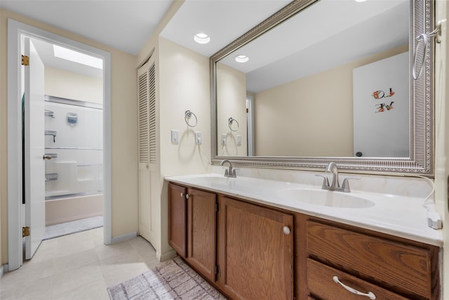 full bath featuring double vanity, enclosed tub / shower combo, a sink, and tile patterned floors