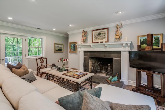 living room with ornamental molding, recessed lighting, a tiled fireplace, and wood finished floors