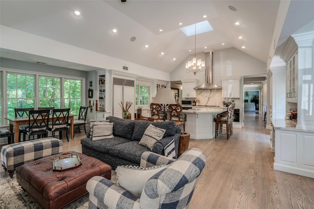 living area featuring light wood-type flooring, a wealth of natural light, high vaulted ceiling, and a skylight