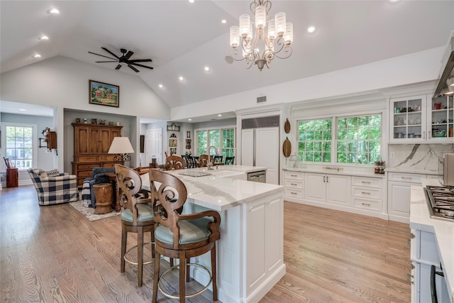 kitchen with glass insert cabinets, light stone countertops, pendant lighting, and white cabinets