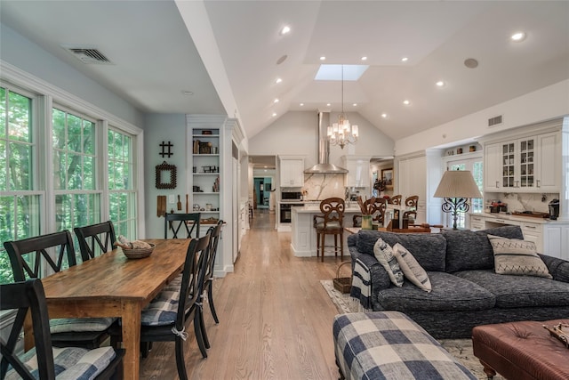 living area featuring a notable chandelier, recessed lighting, visible vents, light wood-style flooring, and high vaulted ceiling