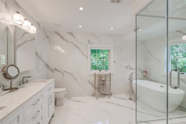 bathroom featuring marble finish floor, stone wall, a freestanding tub, and vanity