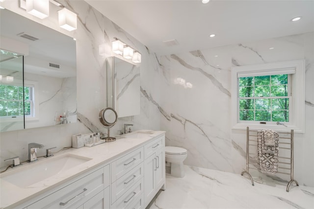 bathroom featuring stone wall, toilet, a sink, visible vents, and marble finish floor