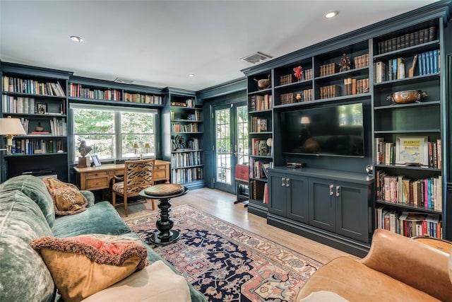 living room featuring light wood-style flooring, visible vents, french doors, and ornamental molding