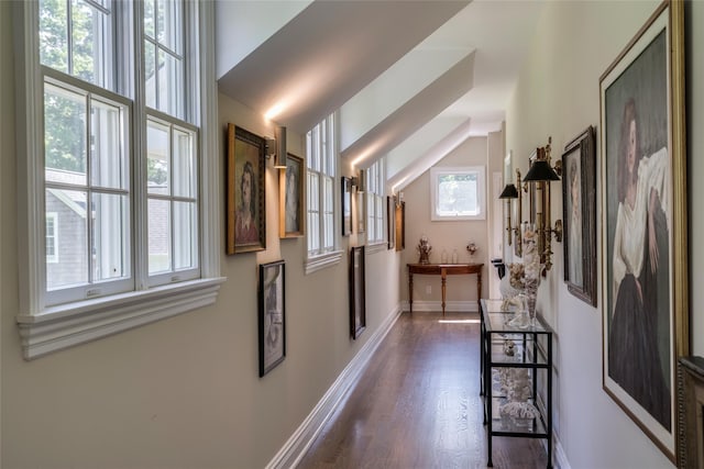 interior space featuring dark wood-style floors, vaulted ceiling, and baseboards