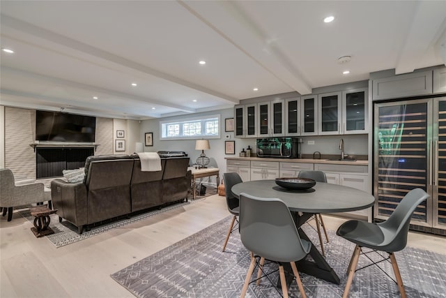 dining space with beverage cooler, light wood-style flooring, beamed ceiling, and recessed lighting