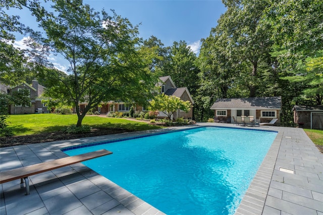 outdoor pool with a patio, a lawn, a storage structure, an outdoor structure, and a diving board