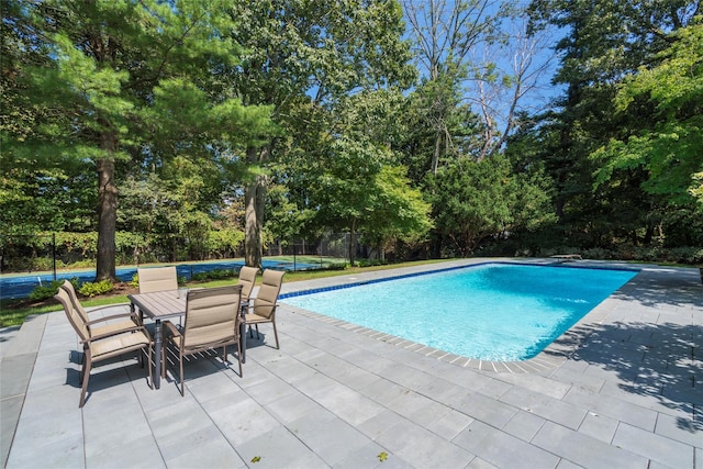 pool featuring outdoor dining space, a patio area, and fence