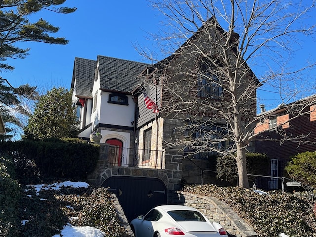 view of home's exterior featuring stone siding, a shingled roof, and stucco siding