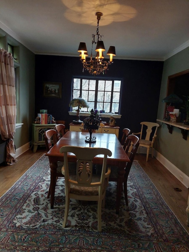 dining room with a chandelier, crown molding, baseboards, and wood finished floors