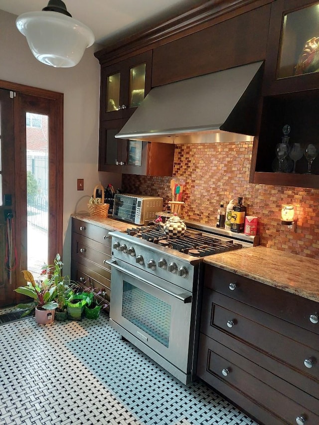 kitchen with dark brown cabinetry, glass insert cabinets, island exhaust hood, high end stove, and backsplash