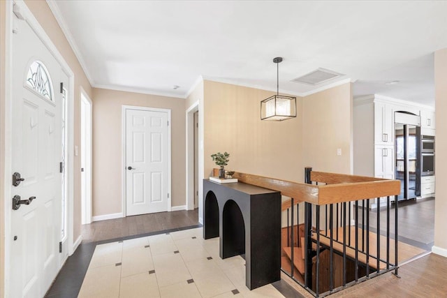 foyer entrance featuring visible vents, baseboards, light wood-style flooring, and crown molding