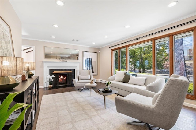 living room featuring a fireplace with flush hearth, recessed lighting, crown molding, and wood finished floors