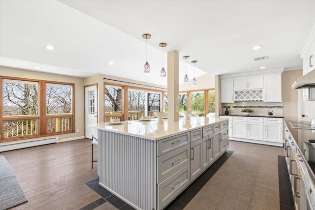 kitchen featuring visible vents, electric cooktop, tasteful backsplash, a kitchen island, and baseboard heating