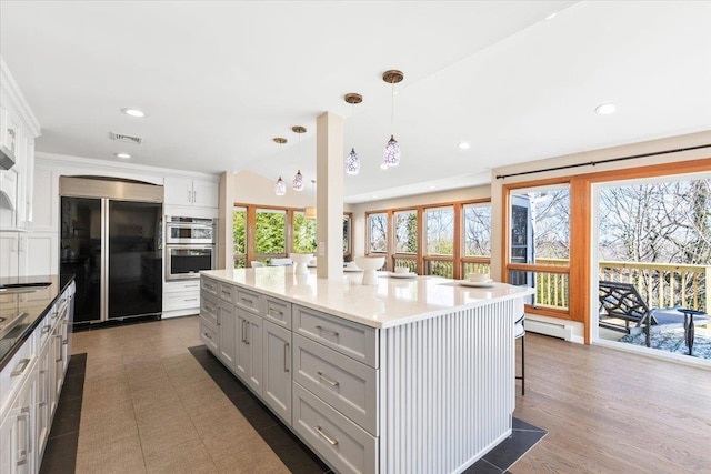 kitchen with a wealth of natural light, double oven, baseboard heating, and built in fridge