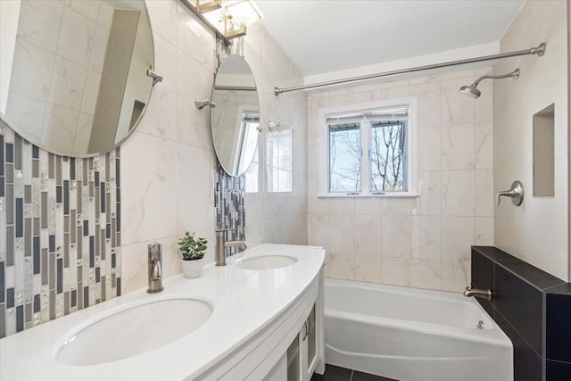 full bathroom featuring shower / tub combination, tile walls, double vanity, and a sink