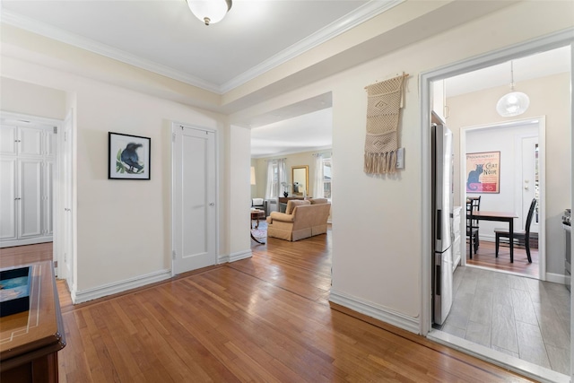 hall featuring ornamental molding, hardwood / wood-style floors, and baseboards