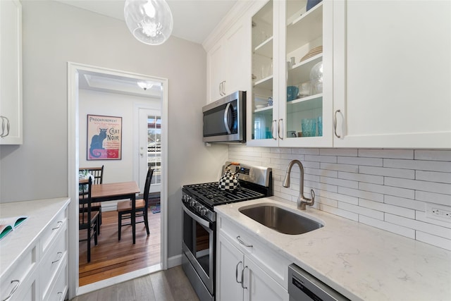 kitchen with glass insert cabinets, dark wood-type flooring, a sink, stainless steel appliances, and backsplash