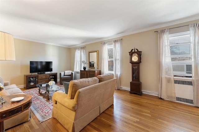 living area with baseboards, radiator heating unit, light wood-style flooring, and crown molding