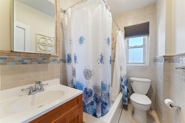 bathroom with shower / tub combo, toilet, tile patterned floors, vanity, and tile walls