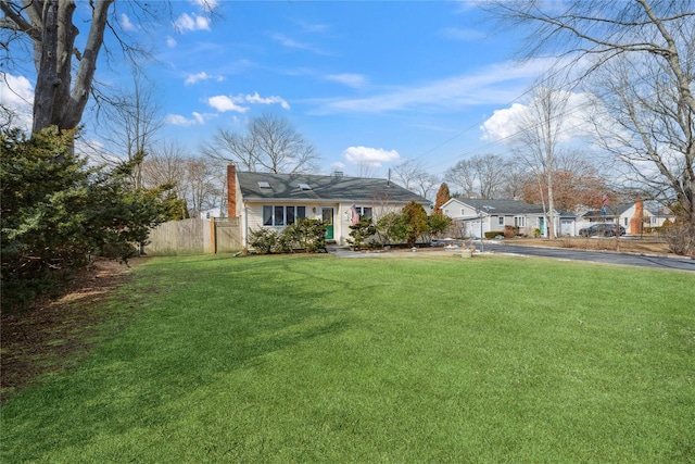 view of front of property with a chimney, a front yard, and fence